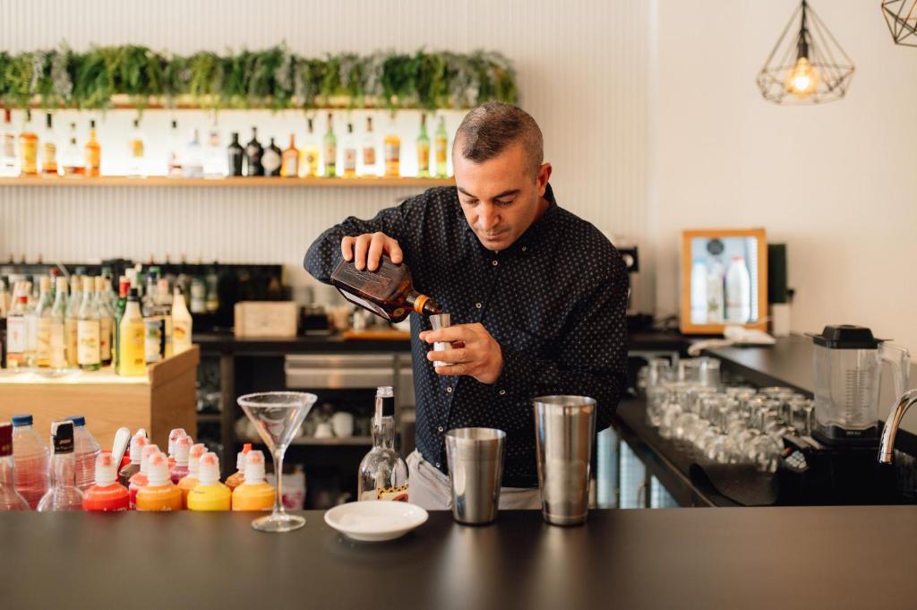 a man standing at a bar pouring a drink at Comitas Floramar in Cala Galdana