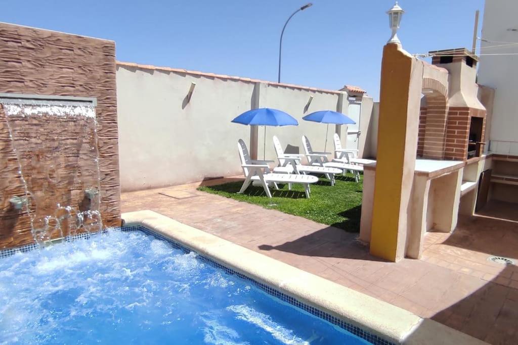ein Pool mit Stühlen und Sonnenschirmen neben einem Gebäude in der Unterkunft La casita de Toledo, cerca de Puy Du Fou in Barcience
