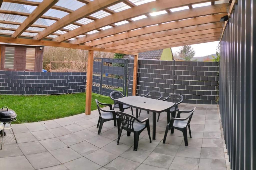 a patio with a table and chairs under a wooden pergola at Ferienhaus Brigitte in Dichtelbach