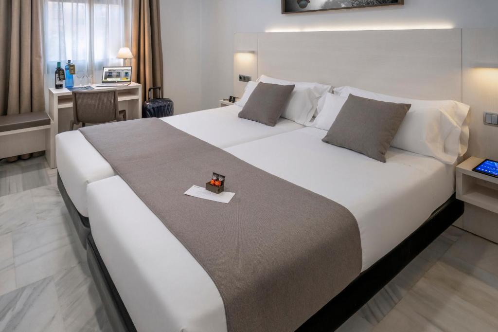 a large white bed in a room with a desk at SERHS Carlit Boutique Hotel in Barcelona