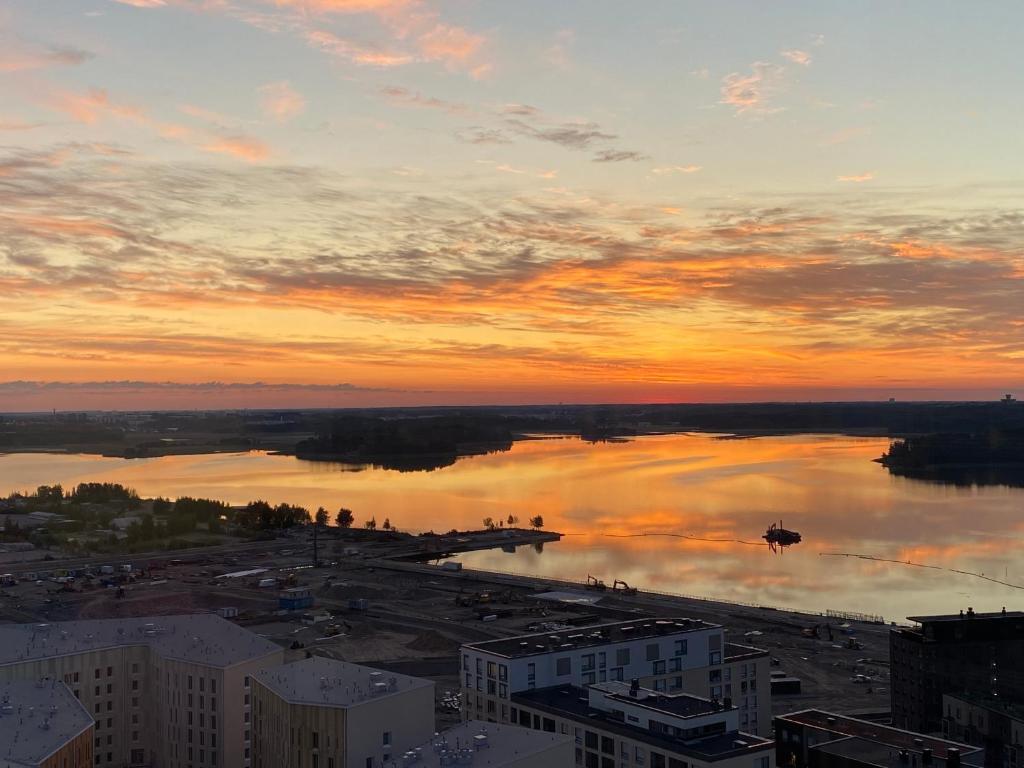 um pôr-do-sol sobre uma grande massa de água em Waterfront 1 Bedroom Skyscraper Suite - 18th Floor - Free Garage Parking em Helsínquia