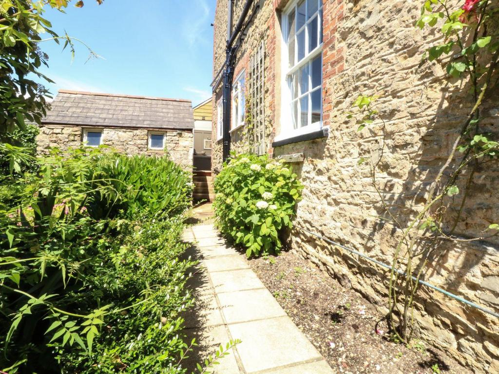 a stone building with a window and a garden at The Apple Loft at Jordan House in Weymouth