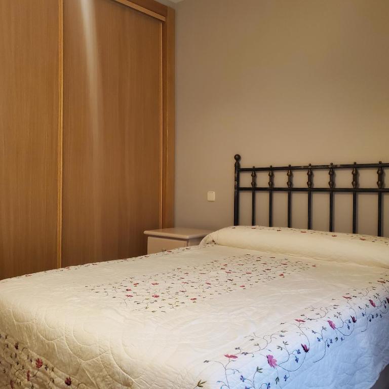 a bed with a white blanket with flowers on it at VUT Casa abuela Antonia in El Barco de Ávila
