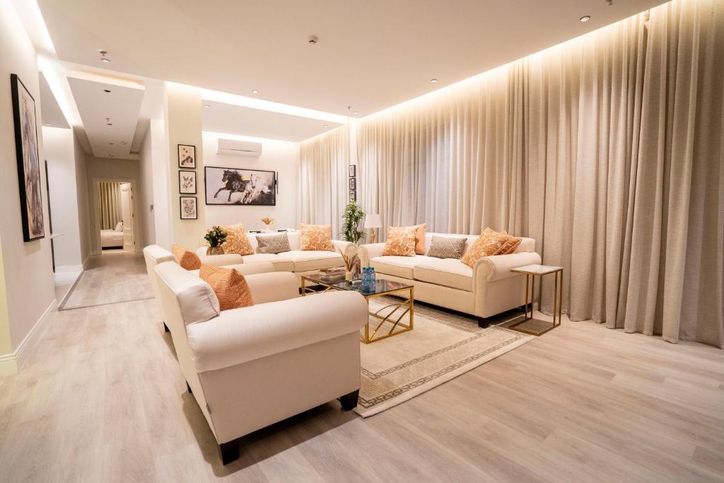Riyadh Comfort Stay - Luxury الملقا Almalqa, 3 Bedrooms في الرياض: غرفة معيشة مع كنب ابيض وطاولة