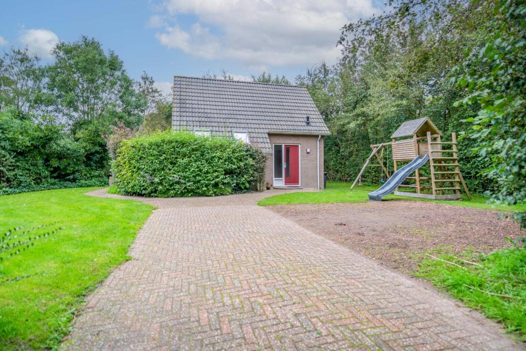 una casa con un tobogán y un parque infantil en Nieuwlanderweg 51 en De Waal