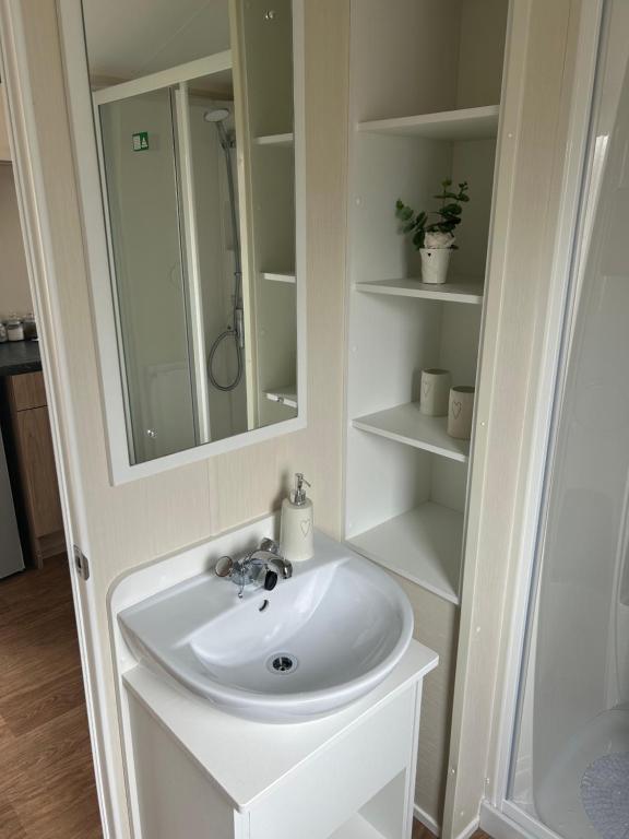 a white bathroom with a sink and a mirror at McCanns Caravan Marton Mere in Blackpool