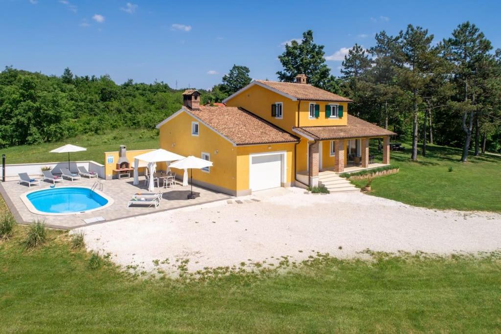 uma casa amarela com uma piscina em frente em Villa Kristina em Pazin