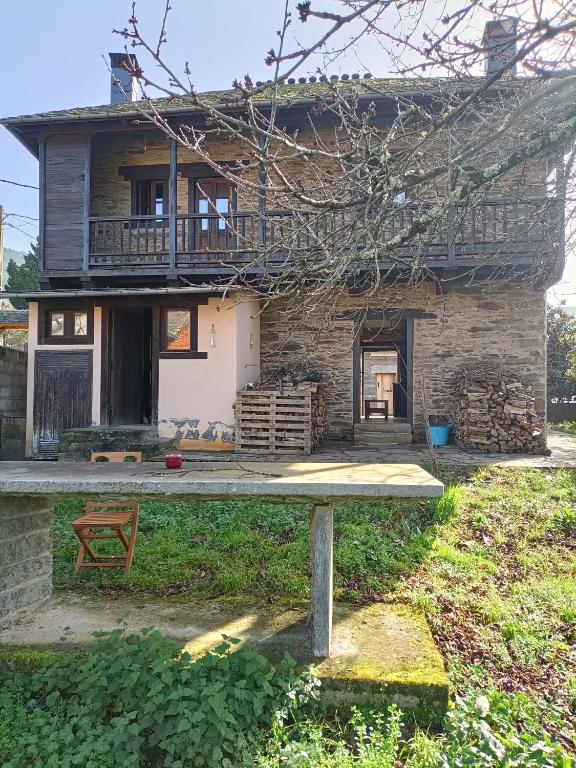 a house with a balcony and a table in front of it at CASA DA RIBEIRA in Quiroga