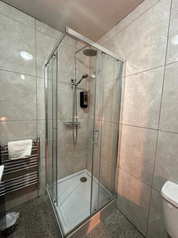 a shower with a glass door in a bathroom at Lamp Light Rooms in Clifden