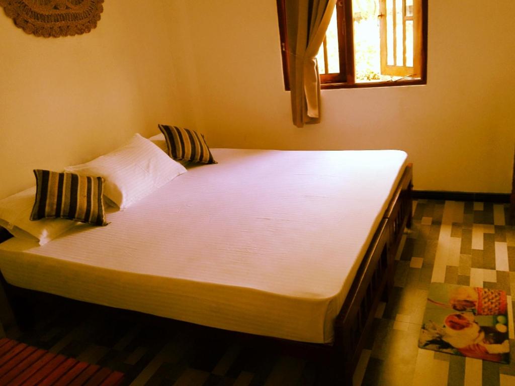 a large white bed in a room with a window at Area 51 Apartment in Mirissa