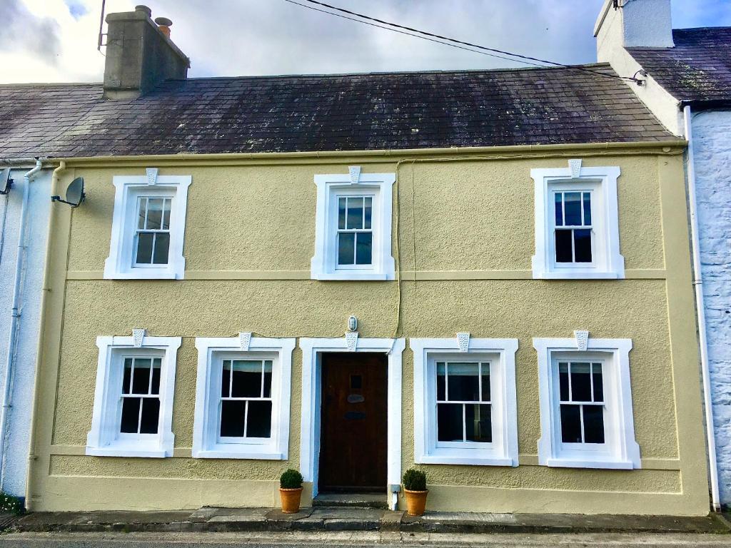 een geel huis met witte ramen en een deur bij Simple Luxury in Brecon Beacons Village House in Llandovery