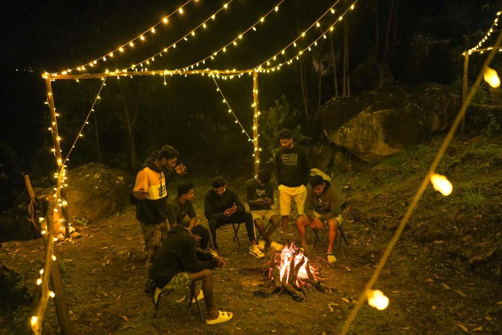 a group of people sitting around a fire at night at Casspo bunk bed in Devikolam