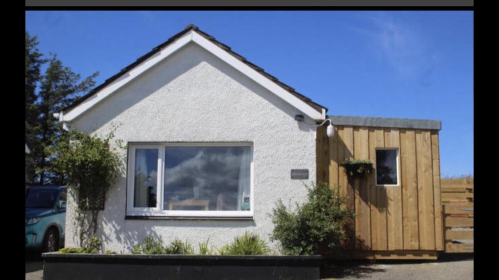 une maison avec une clôture en bois devant elle dans l'établissement Minimorn at Ardmorn holiday accommodation, à Dunvegan