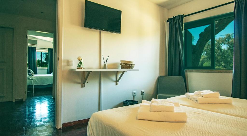 a bedroom with two beds and a tv on the wall at Pine House - Faro Airport, Beach and City Center in Faro