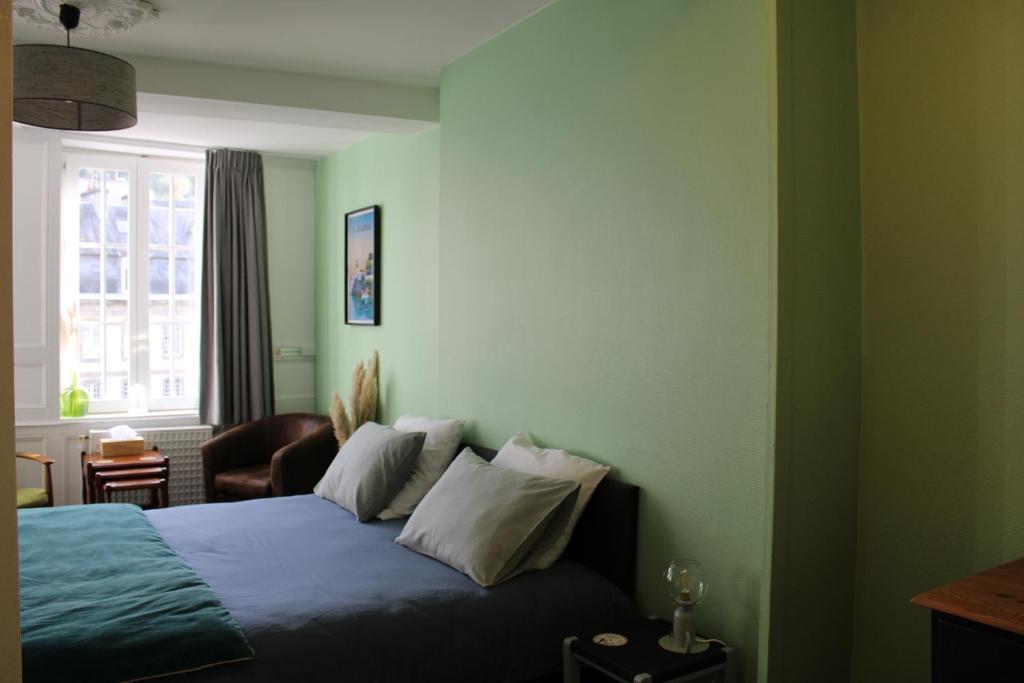 a bedroom with a bed with blue sheets and a window at Au Pied du Viaduc in Morlaix