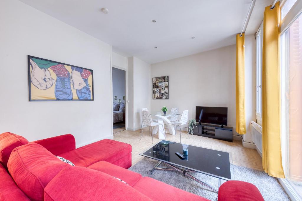 ein Wohnzimmer mit einem roten Sofa und einem TV in der Unterkunft Relaxing, station RER B, Orly, Paris, autonomous access in Massy