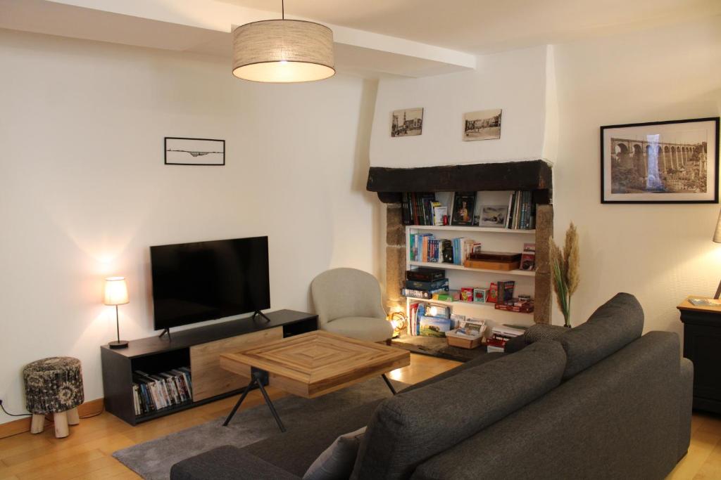 a living room with a couch and a tv at Au Pied du Viaduc in Morlaix