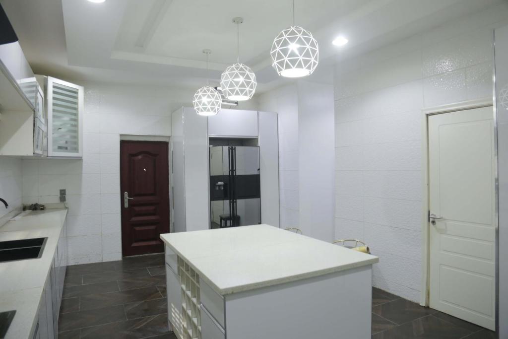 a kitchen with white walls and a counter and pendant lights at 1164 Residence Apartment in Abuja