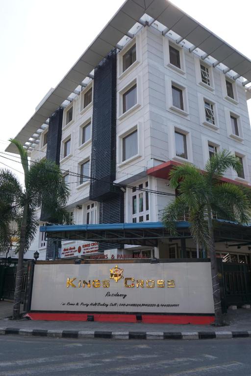 a large white building with palm trees in front of it at Kingscross Residency in Chennai
