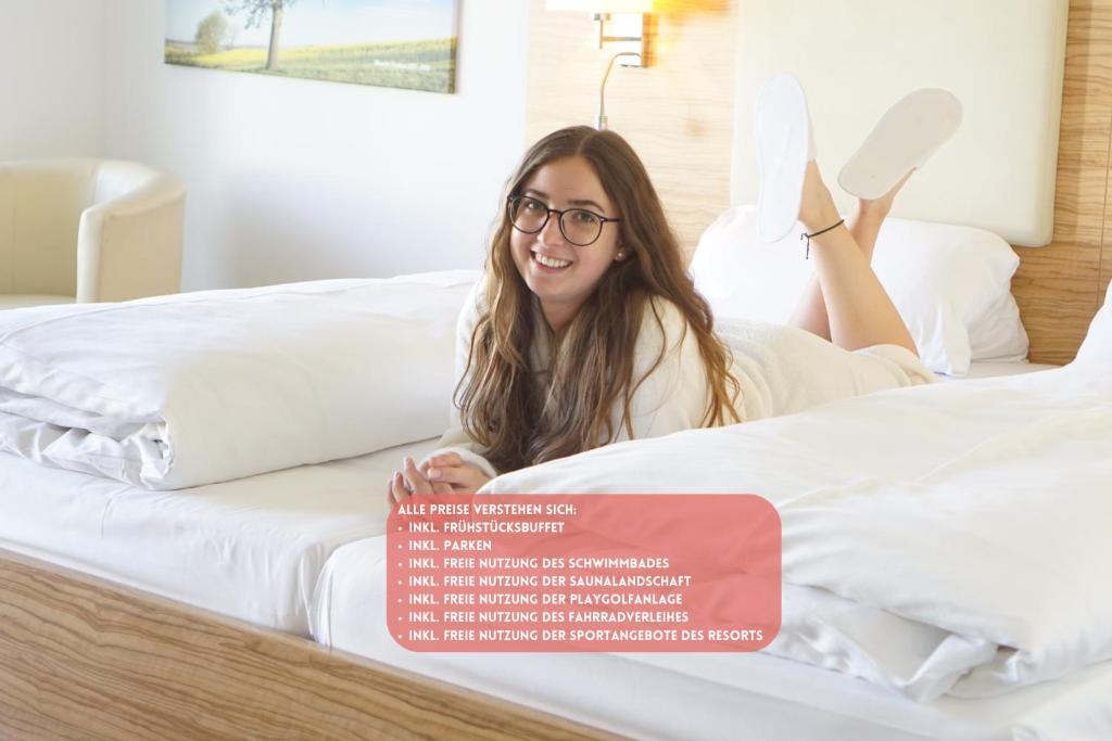 a woman laying on a bed with her feet in the air at Havellandhalle Resort in Seeburg