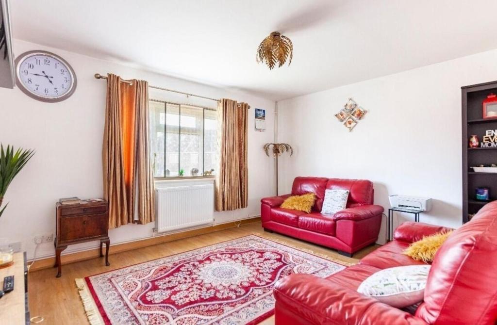 ein Wohnzimmer mit roten Möbeln und einer Uhr an der Wand in der Unterkunft Inviting 2-Bed Apartment in Hounslow in Hounslow
