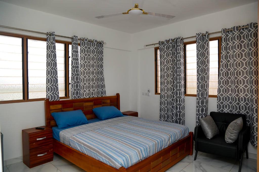 um quarto com uma cama, uma cadeira e janelas em BELLEHAVEN LUXURY APARTMENT em Acra
