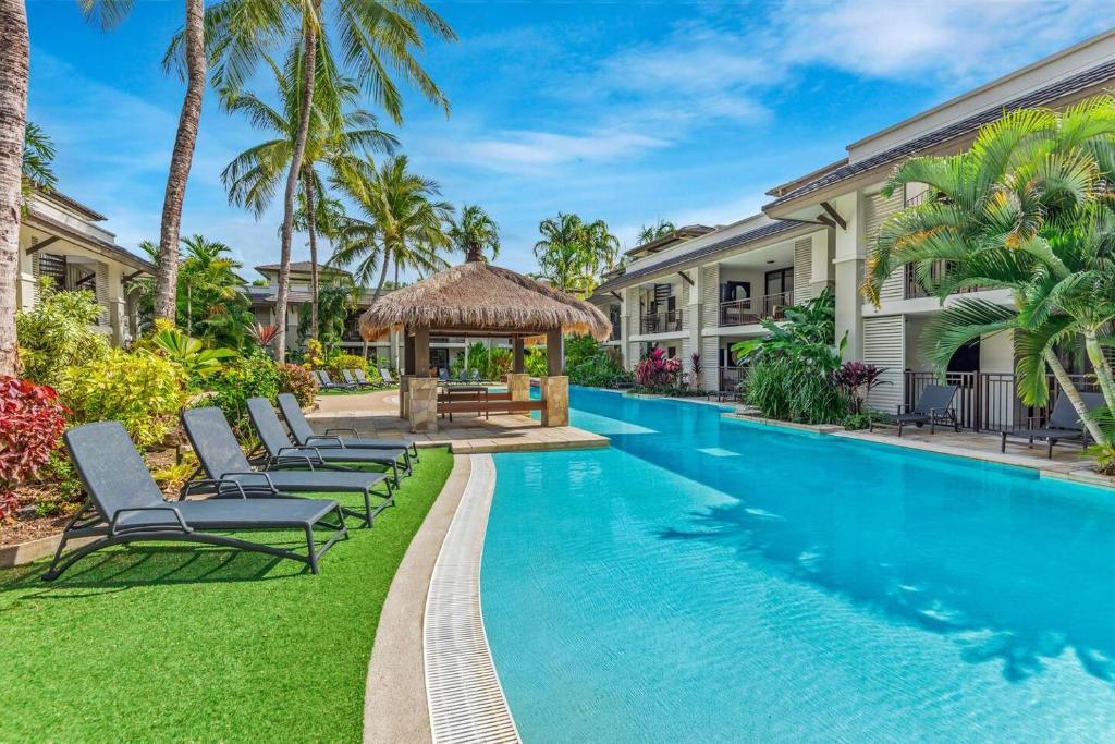 een zwembad in een villa met stoelen en een prieel bij Lagoon Breeze Swim-out Temple Resort Stay in Port Douglas