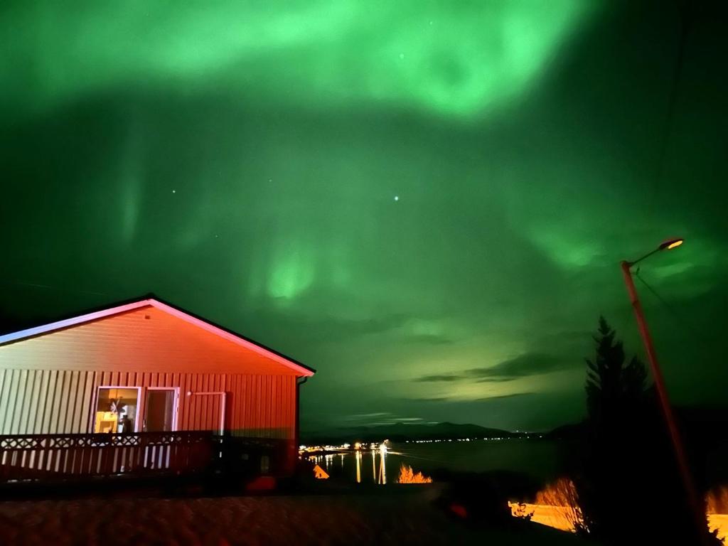 a red building with the green northern lights in the sky at Senja Peak Panorama in Straumstad