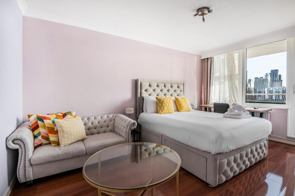 una camera con letto, divano e tavolo in vetro di Two Stunning Bedrooms & Private Balcony & River View a Londra