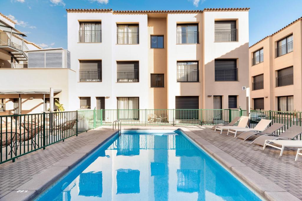 a swimming pool in front of a building at Castell Beach Aparthotel in Castelldefels