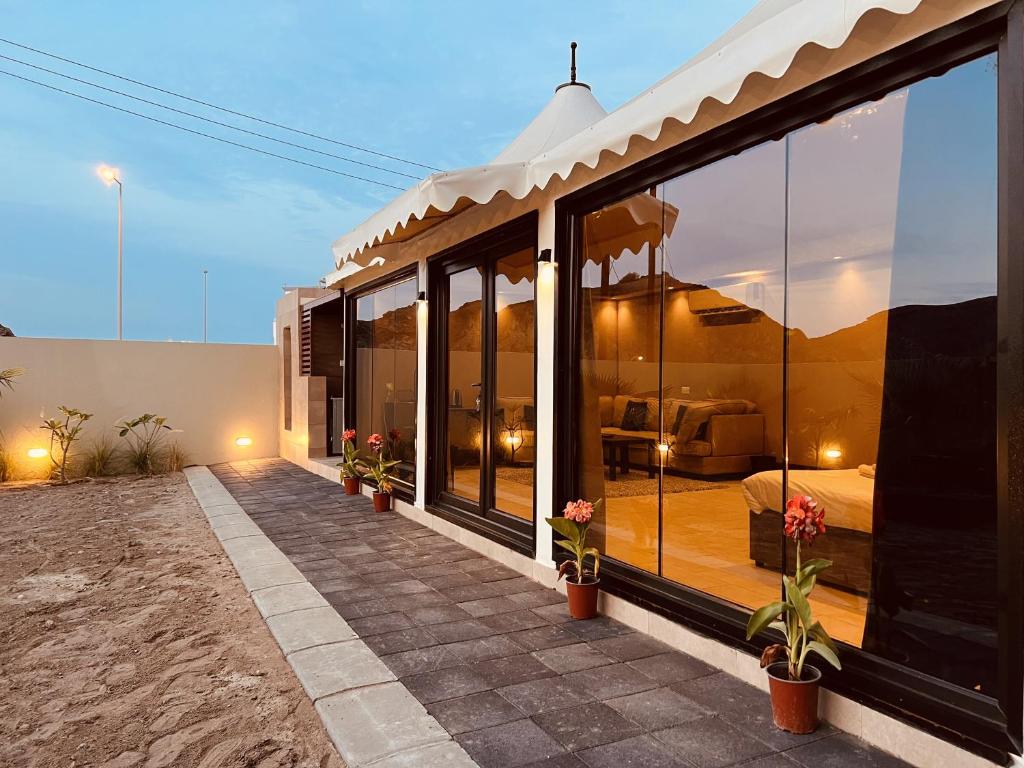 ONE Elegant Cottage near the Beach في مسقط: منزل به نوافذ زجاجية كبيرة على الفناء