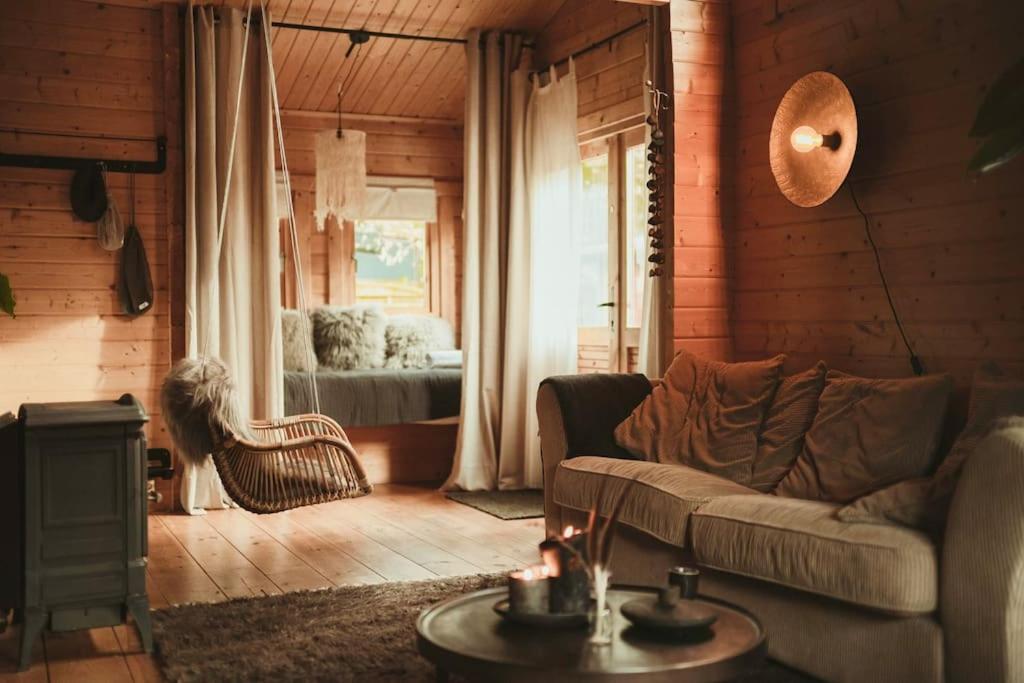 ein Wohnzimmer mit einem Sofa und einem Fenster in der Unterkunft A magical get away with bath and forest view in Putten