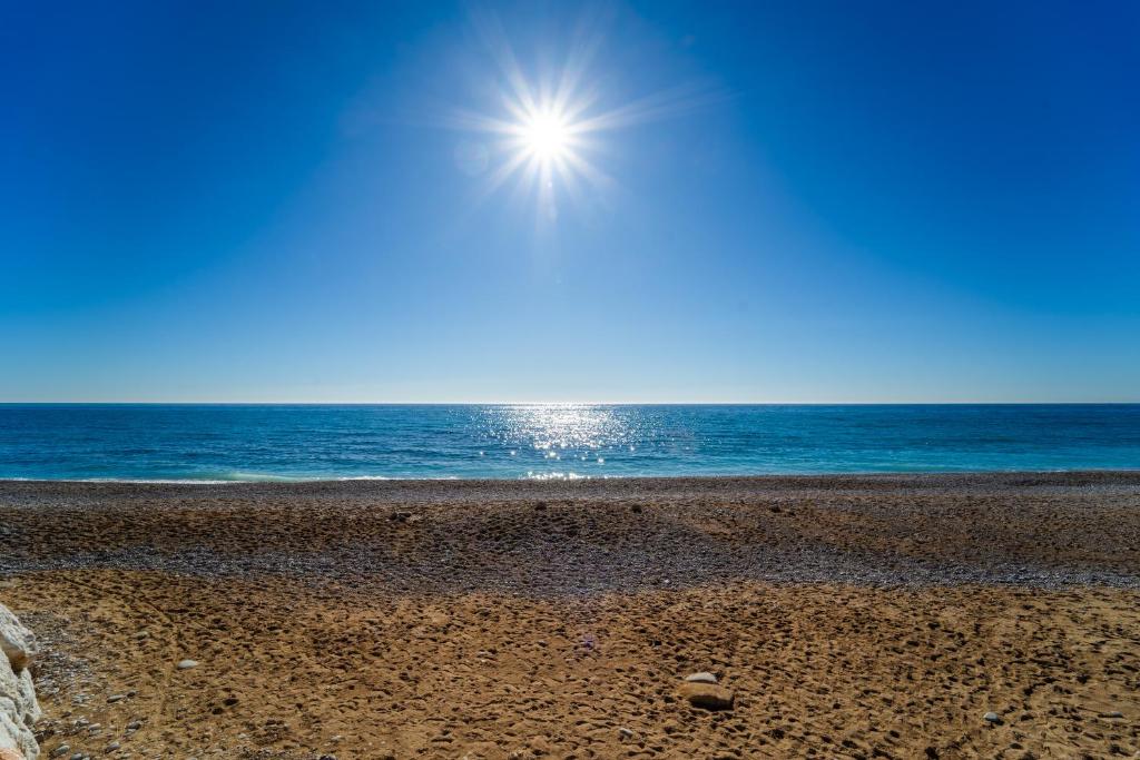 una playa con el sol brillando sobre el océano en Tranquilidad a la orilla del mar, en Villajoyosa