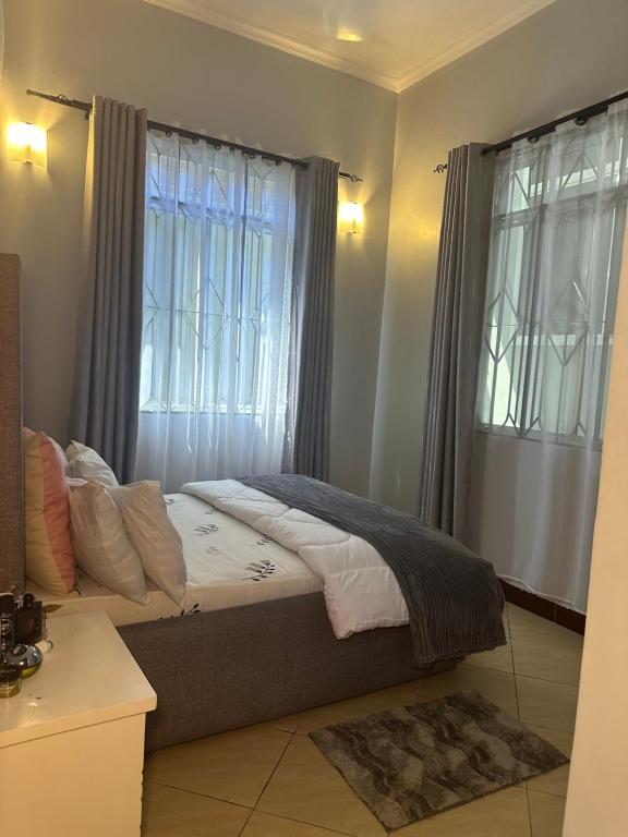 sypialnia z łóżkiem i oknem z zasłonami w obiekcie Stay with soniyah w mieście Dar es Salaam