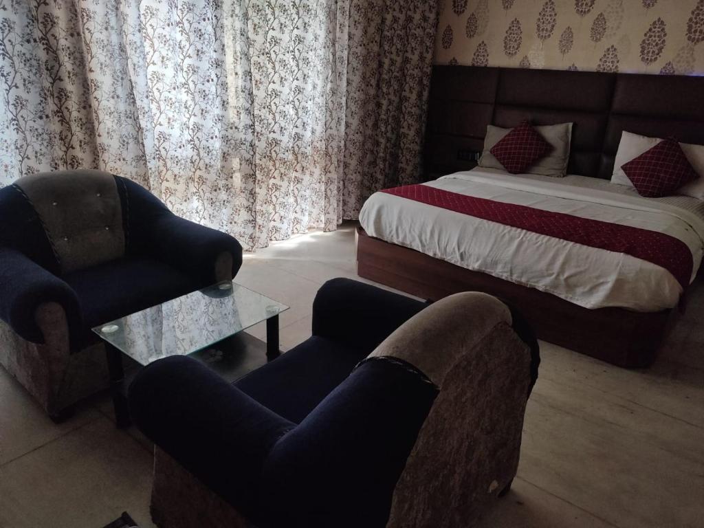 een slaapkamer met een bed en 2 stoelen en een tafel bij Hotel Rose Garden - Janakpuri in New Delhi