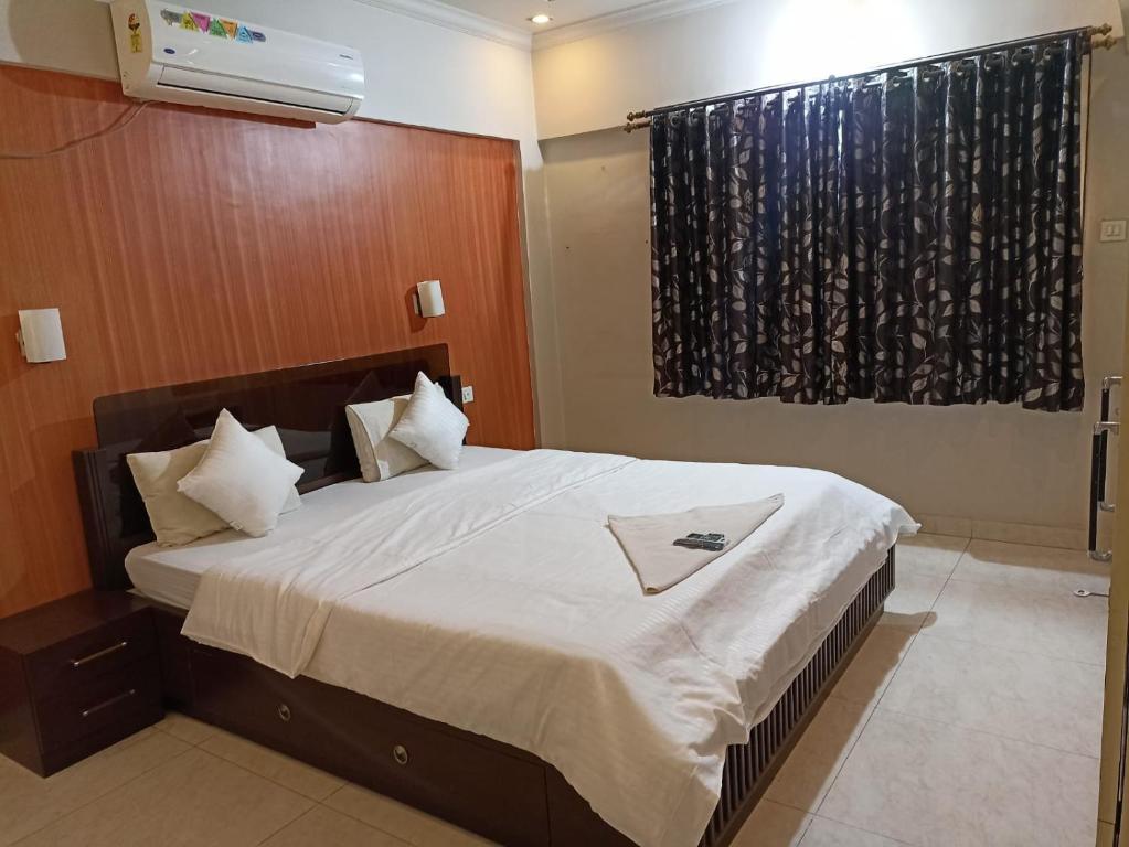 una camera da letto con un grande letto con lenzuola bianche di gargi vill guest house a Pune