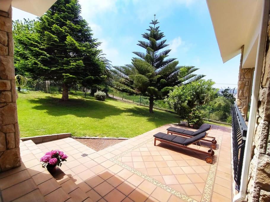 un patio con un banco y un pino en Chalet con magníficas vistas al mar en Perlora