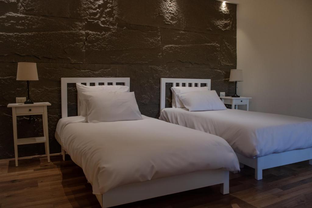 2 camas con sábanas blancas y almohadas en una habitación en Saraya locanda en Al Salt