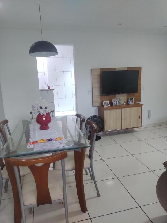 ein Esszimmer mit einem Tisch mit Stühlen und einem TV in der Unterkunft Casa Aconchegante in Cabo Frio