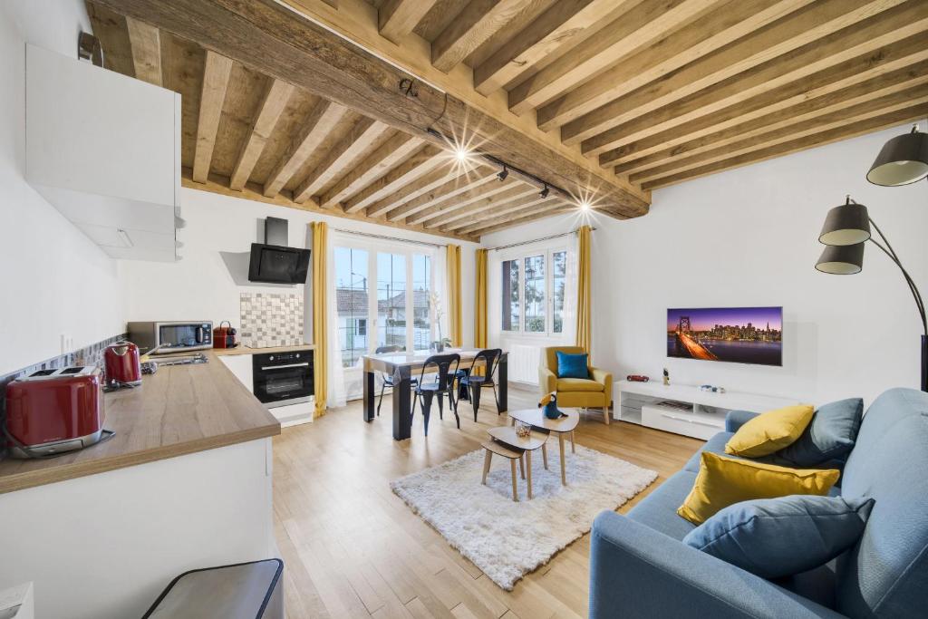 un soggiorno e una cucina con un divano blu e un tavolo di Climats des Échaliers a Beaune