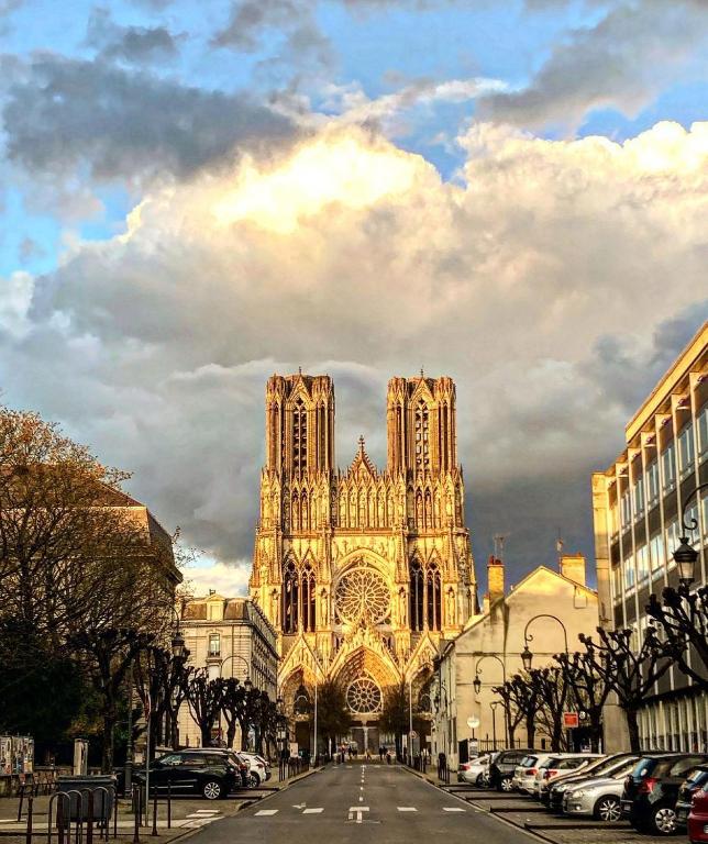 a large cathedral with cars parked in front of it at La Demeure des Sacres - Cathédrale in Reims