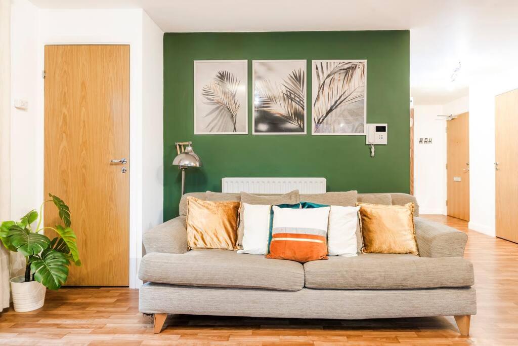 um sofá numa sala de estar com pinturas na parede em Emerald Retreat - City Centre - Free Parking, Fast WiFi and Smart TV by Yoko Property em Derby