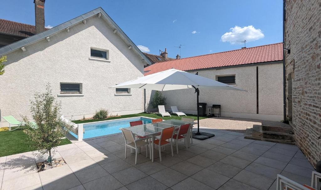 une terrasse avec une table, un parasol et une piscine dans l'établissement La Maison de Caro, à Gevrey-Chambertin