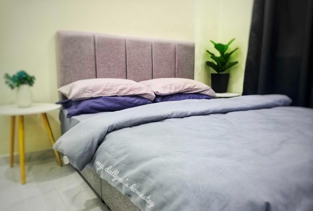 a bed with purple and pink pillows in a bedroom at My Dallyne's Homestay at The Heights Residence, Ayer Keroh, Melaka in Ayer Keroh