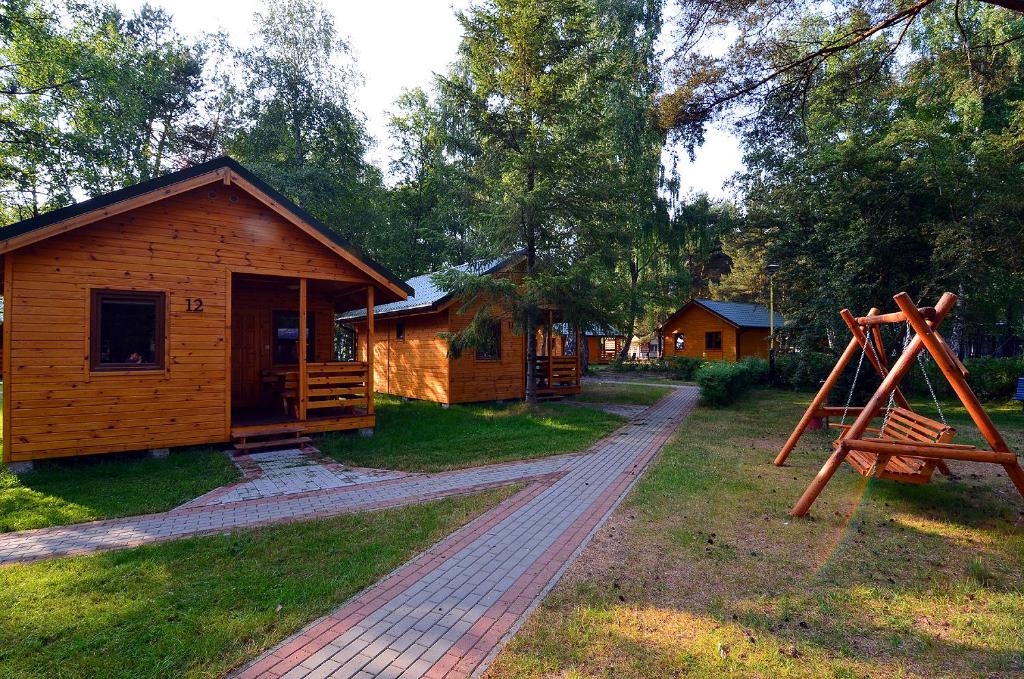 uma cabana de madeira com um caminho ao lado de uma casa em Bajkowy Las em Mielno