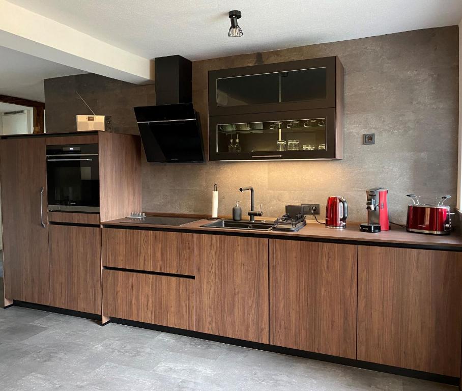 a kitchen with wooden cabinets and a sink and a stove at Haus Mariechen Whg 2- 5-Sterne-DTV-Klassifizierung- nähe Silbersee mit Terrasse & Sauna, in Frielendorf