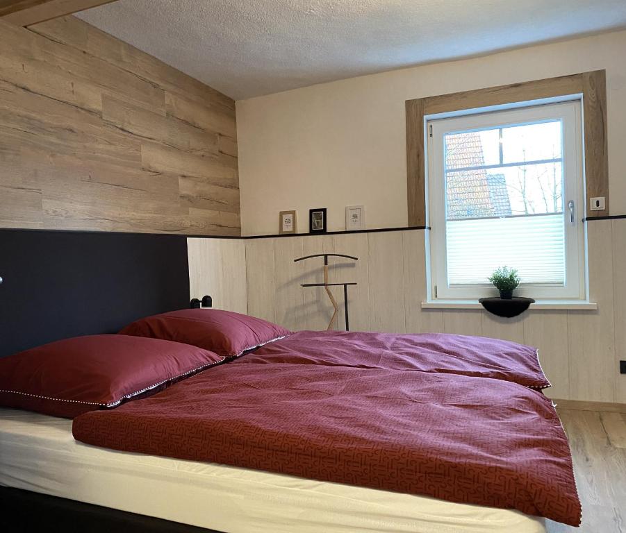a bedroom with a large red bed with a window at Haus Mariechen Whg 2 in der Nähe zum Silbersee mit gemütlicher Terrasse & Sauna in Frielendorf