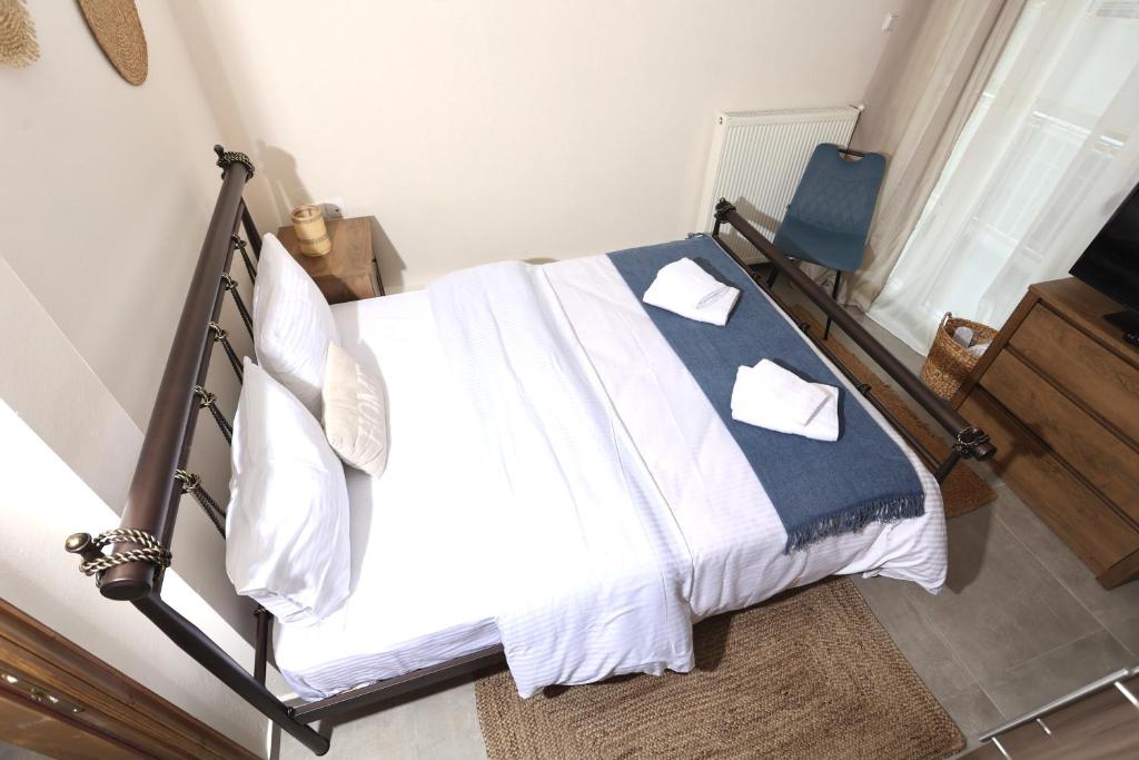Un dormitorio con una cama con sábanas blancas y una silla azul. en Στυλ & άνεση στο κέντρο La Maison 12 Ανακαινισμένο διαμέρισμα, en Larisa