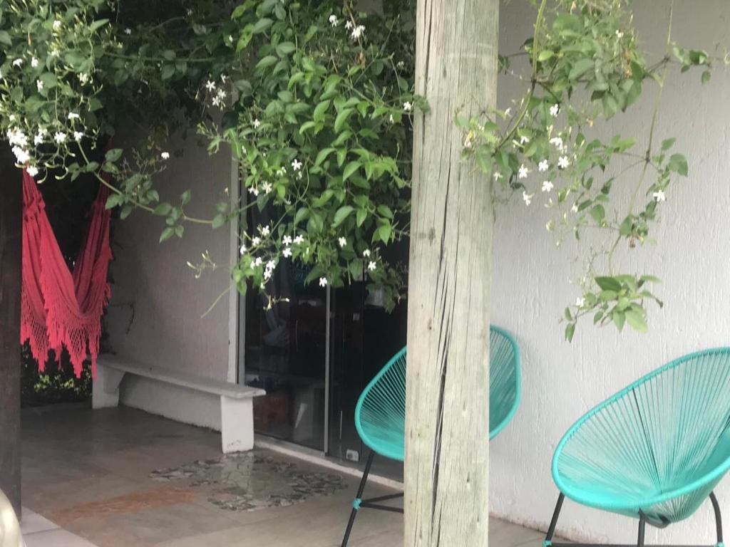 two blue chairs sitting next to a wall with flowers at Casa Jasmim in Imbituba