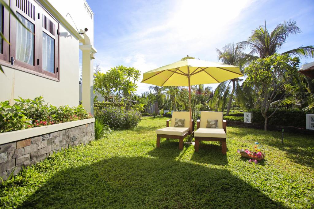 eine Terrasse mit 2 Stühlen und einem Sonnenschirm in der Unterkunft Green Boutique Villa in Hoi An